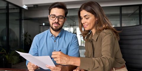 A man reviews a document with a woman. 