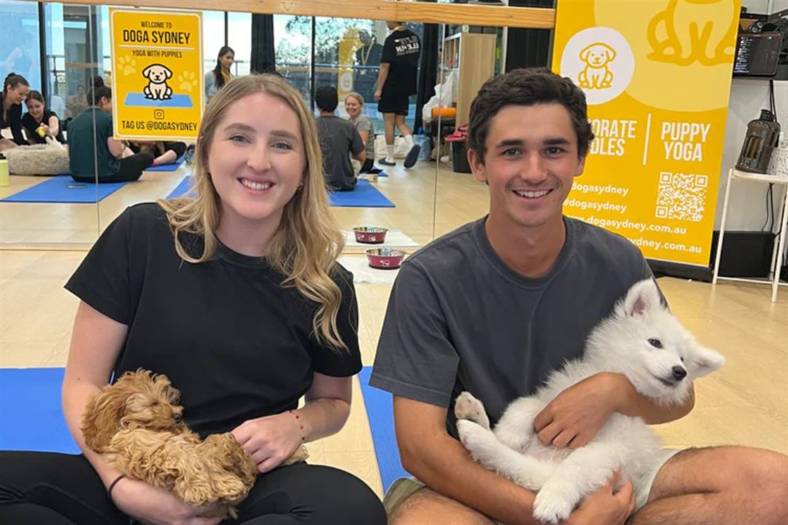 Smiling man and woman holding two small and fluffy puppies