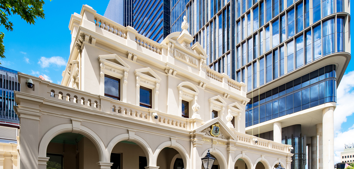 Modern day image of the town hall's original exterior standing in front of a modern high rise building