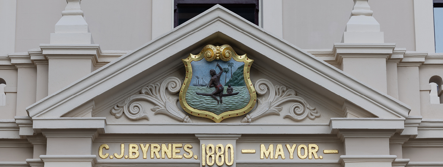 Close up of the town hall's triangular decorative wall surface over the entrance, with the text C. J. Byrnes, 1880, Mayor and a crest above it