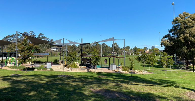 Playspace and picnic area with shade cover, field in background