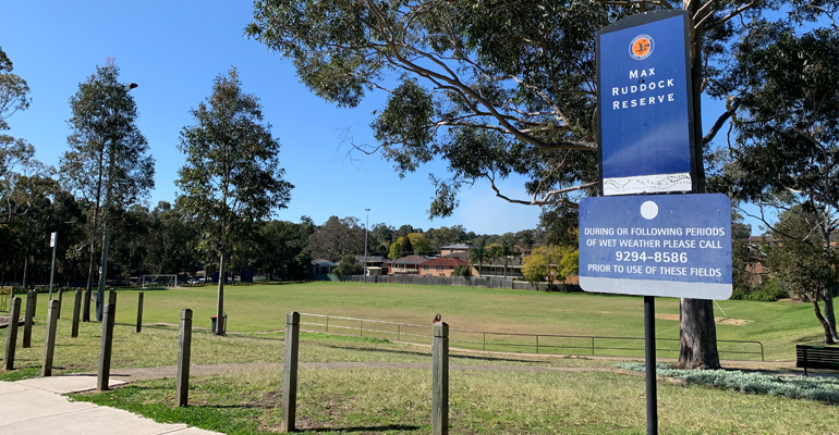 Max Ruddock Reserve sign with pole fencing and sports field in background
