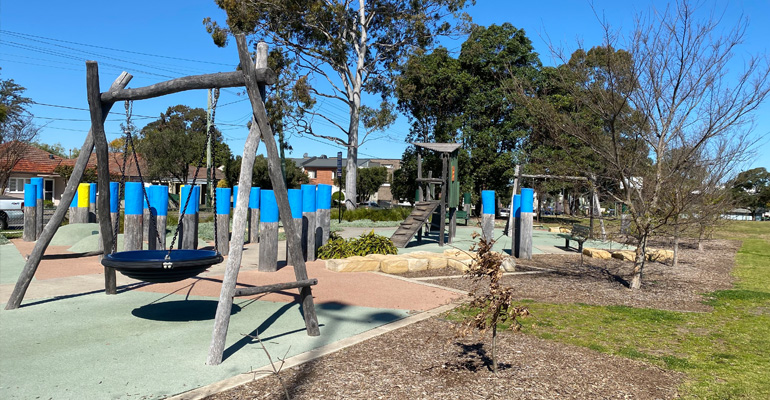 Playspace with large swing, wooden poles and house
