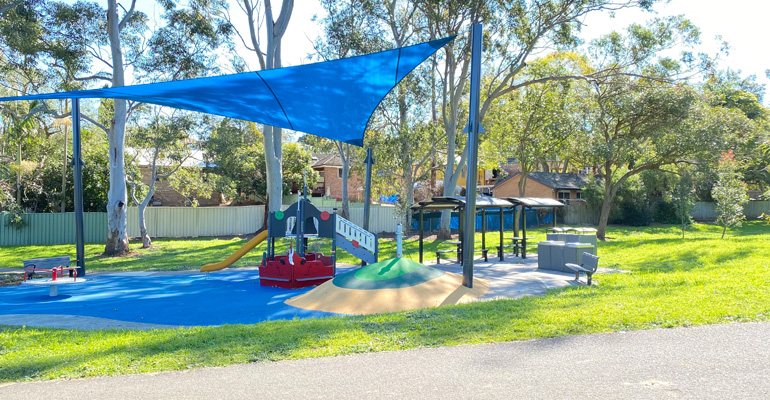 Play space with equipment with shade cloth, park benches and picnic areas