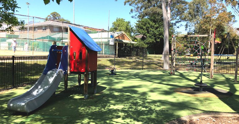 Small play equipment with slide, rocker and swings, tennis court at back