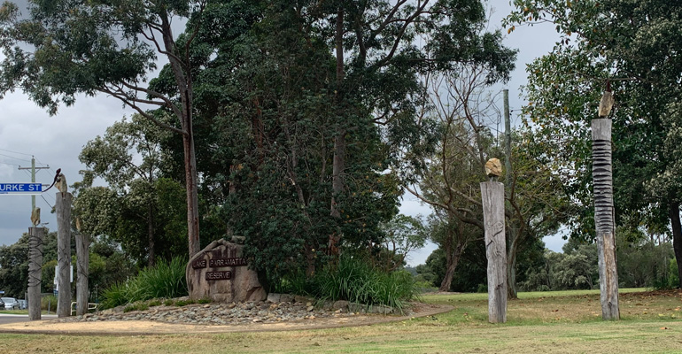 Lake Parramatta Reserve sign on large stone, totem poles on both sides