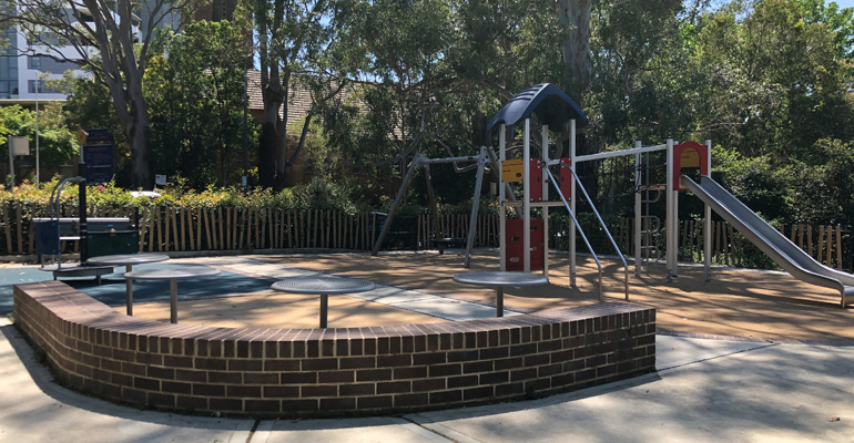 Playground with low brick wall and round tables; play equipment