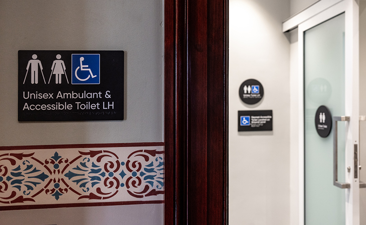 Close up image of a unisex ambulant and accessible toilet sign on the wall