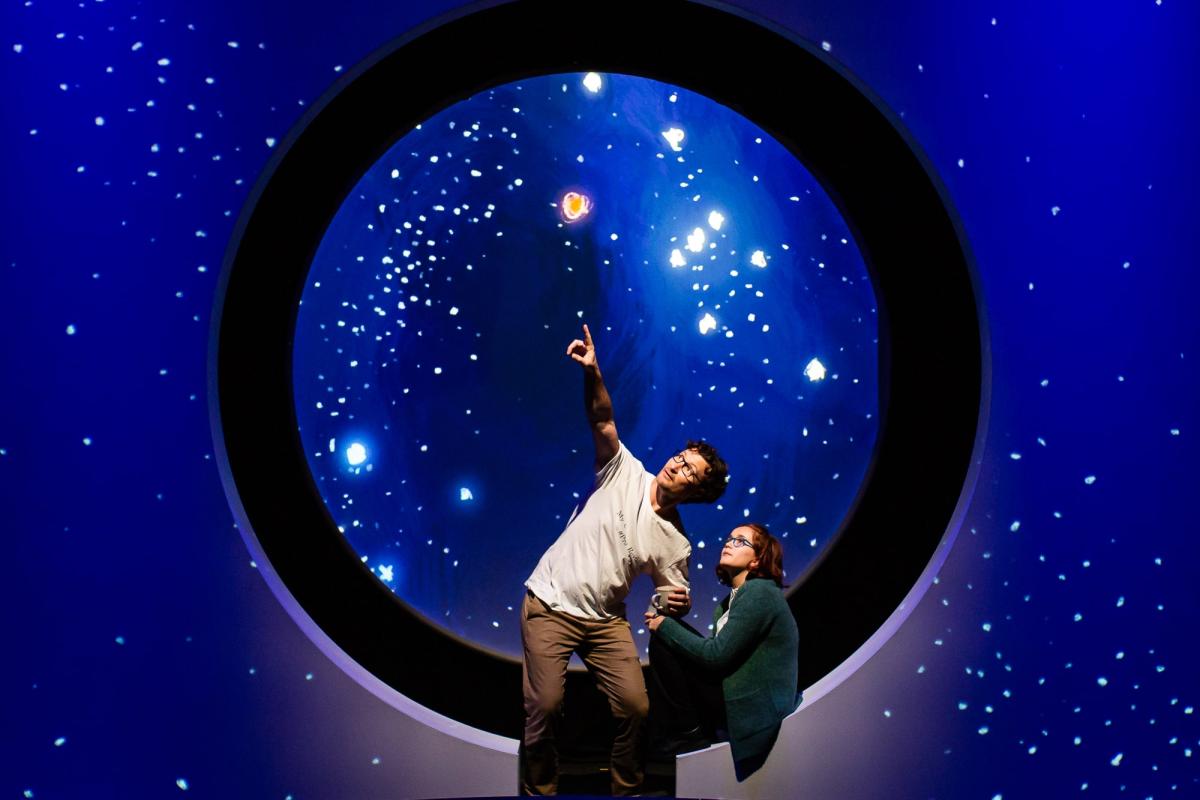 Two people looking at the sky with a starlight background