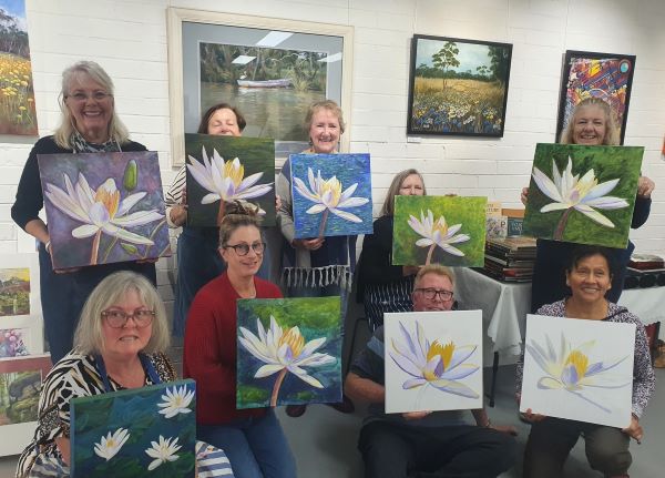 Women and men holding up their painting 