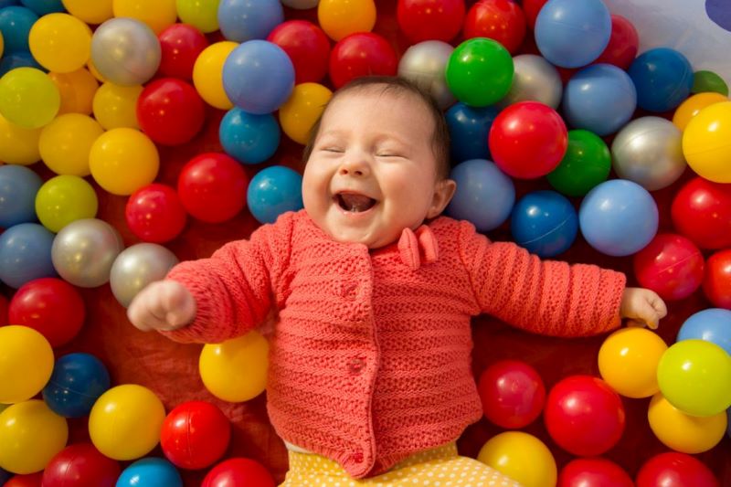Baby laughing in pool of balls 
