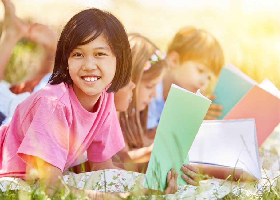 Children reading in the grass on a sunny day