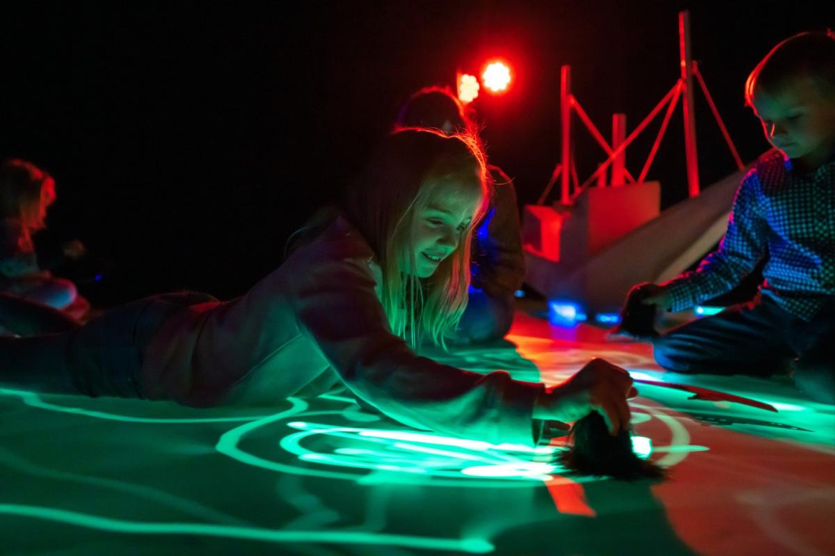 Young girl interacting with light artwork