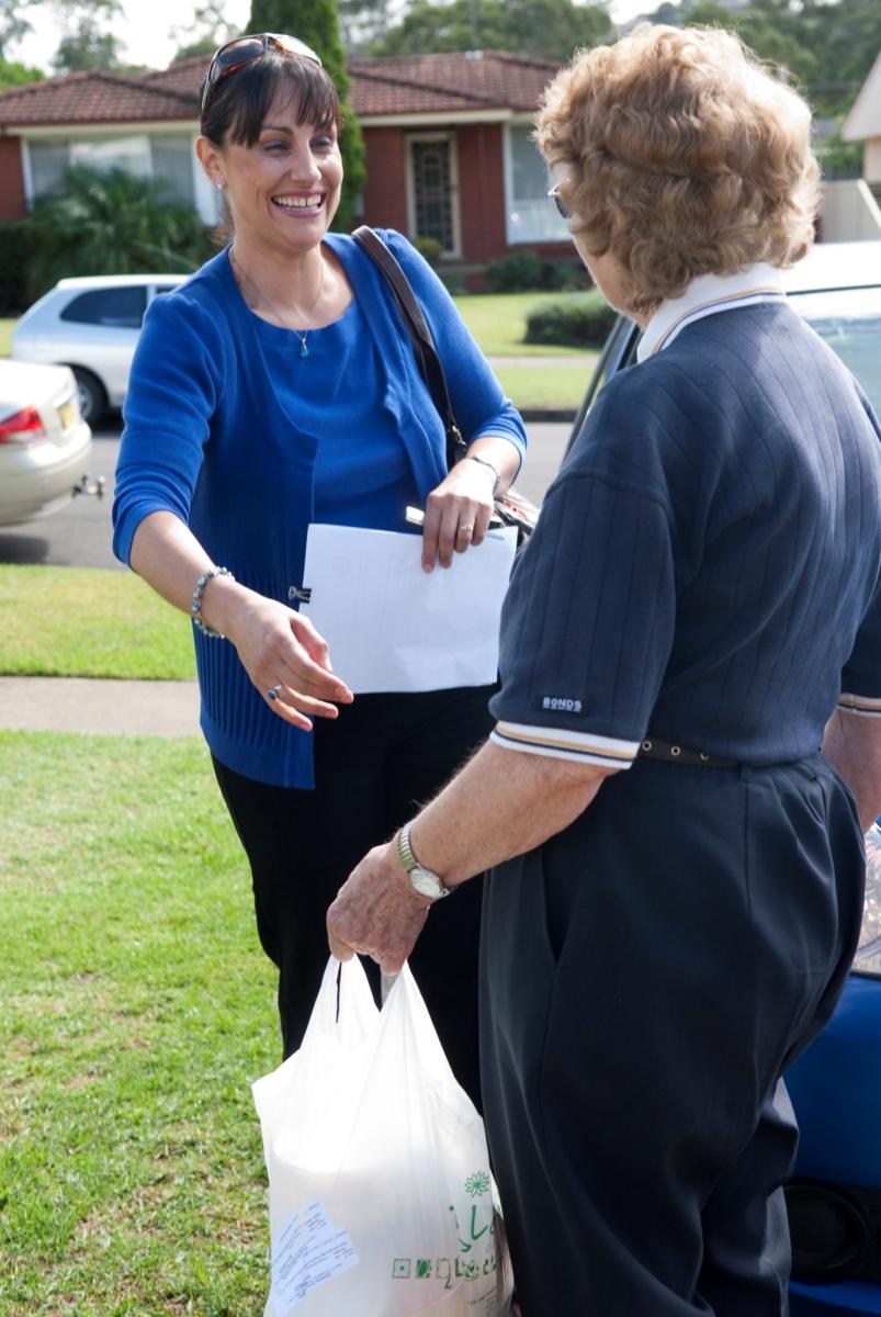 A volunteer assisting an elderly woman.