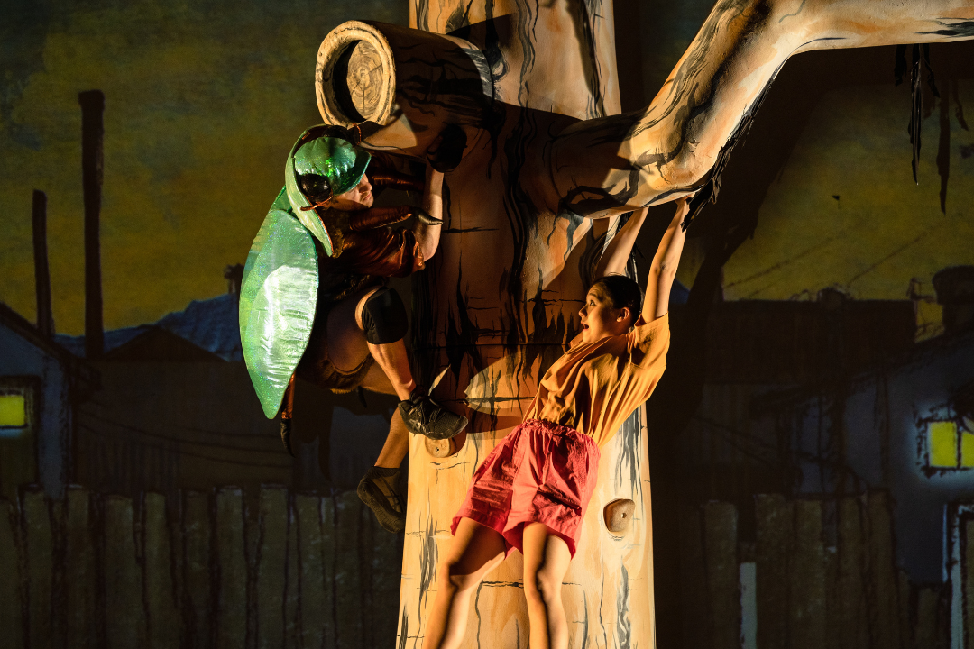 Man dressed as beetle up a tree with young girl