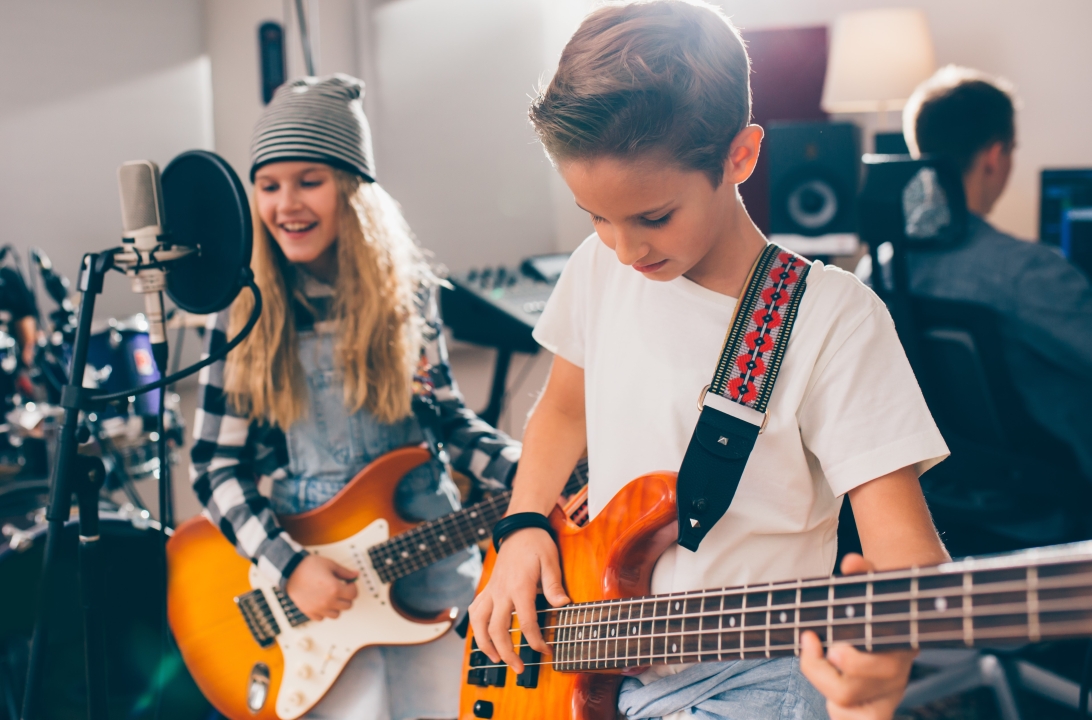 Girl and boy holding guitars in front of microphone