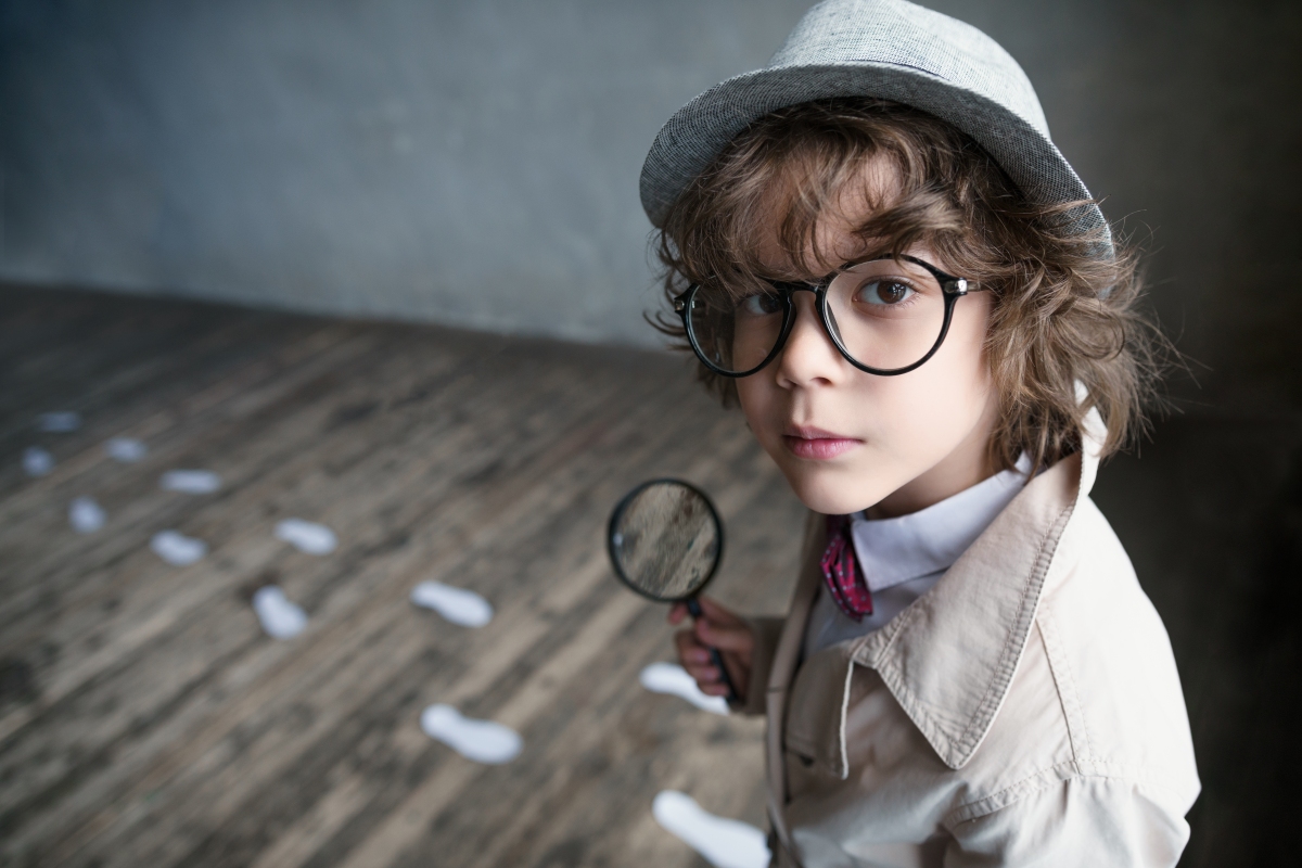Boy in glasses holding a magnifying glass