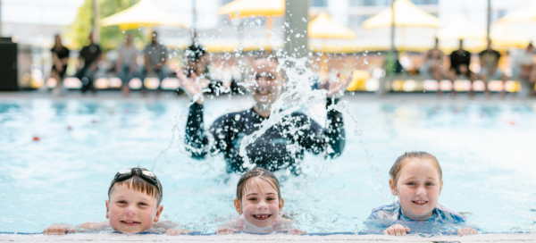 three young swimmers in pool smiling to camera