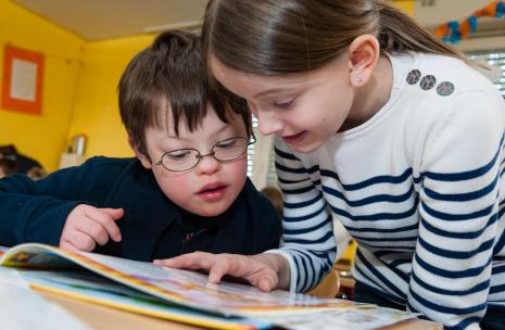: Image of a boy and girl reading a book in an inclusive education setting