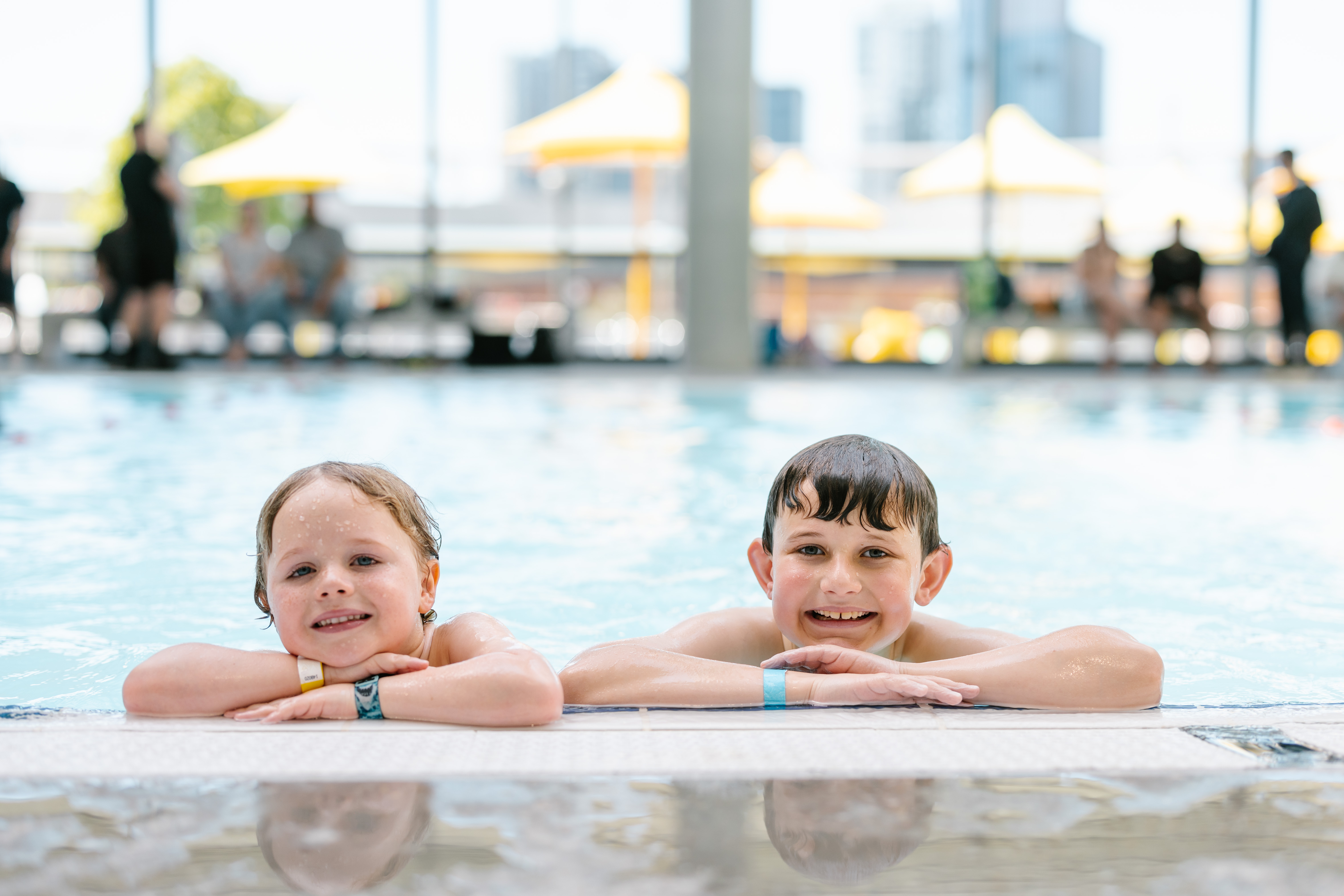 Two kids poolside smiling at camera